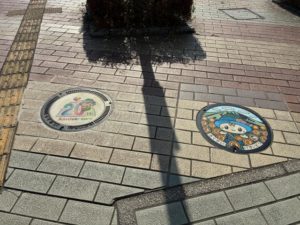 ちっくんと筑西市政20周年記念ロゴのマンホール。